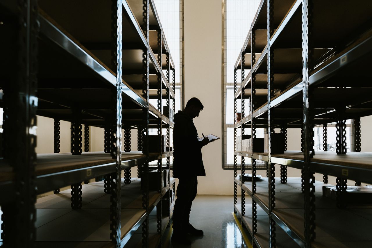 Mastering the First Impression: Your intriguing post title goes here Silhouette of a person checking inventory in an empty warehouse with racks.