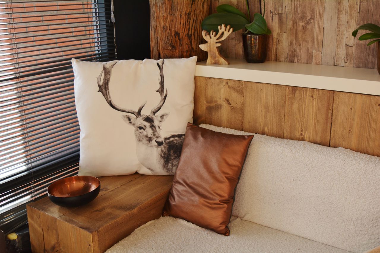 A cozy living space featuring a deer pillow, modern decor, and rustic wooden elements.