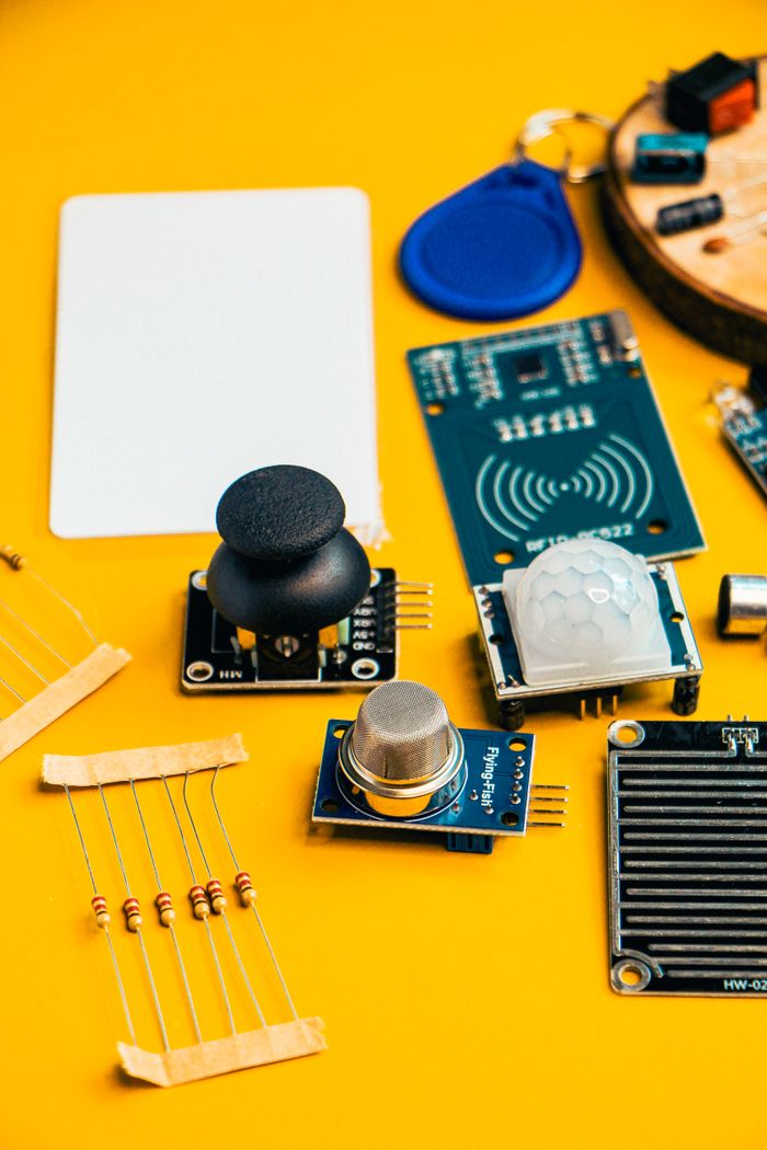 services-01 A top-down view of various electronic components and sensors on a vibrant yellow surface.