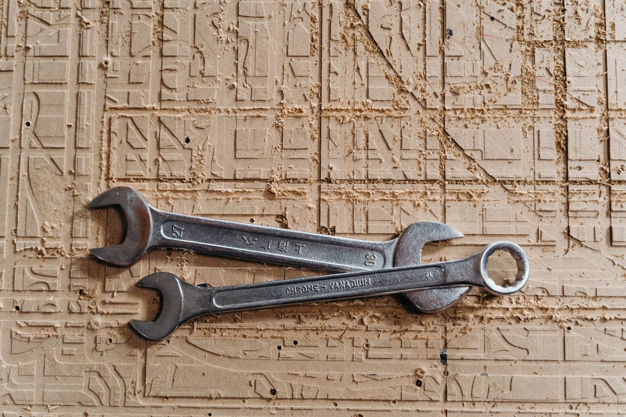 Two metal spanners placed on a textured wooden surface, showcasing industrial tools.